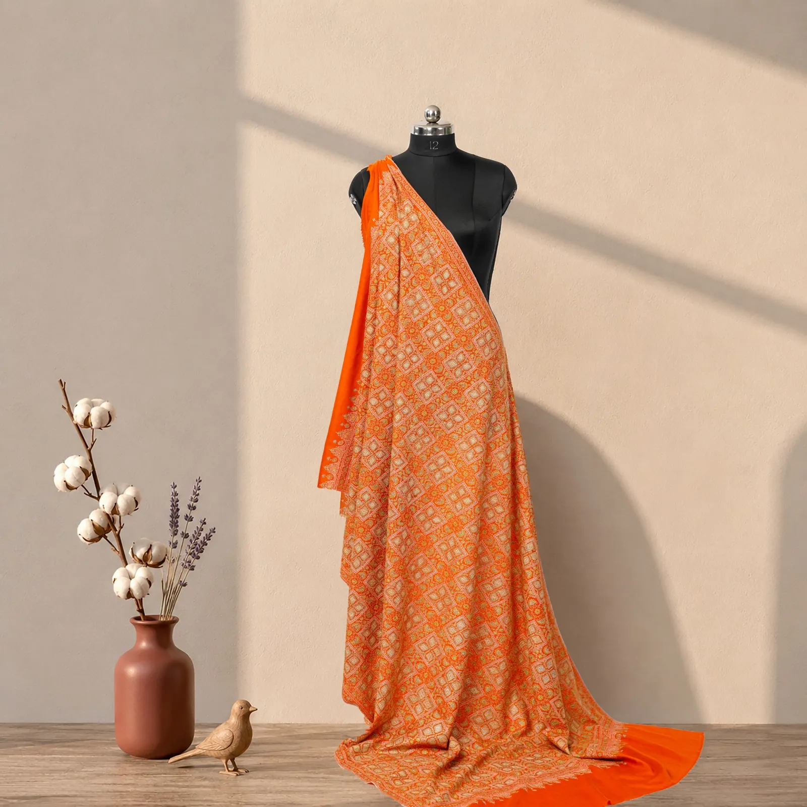 Saffron shawl with cream needlework laid in a lattice across the whole body, on a stand.