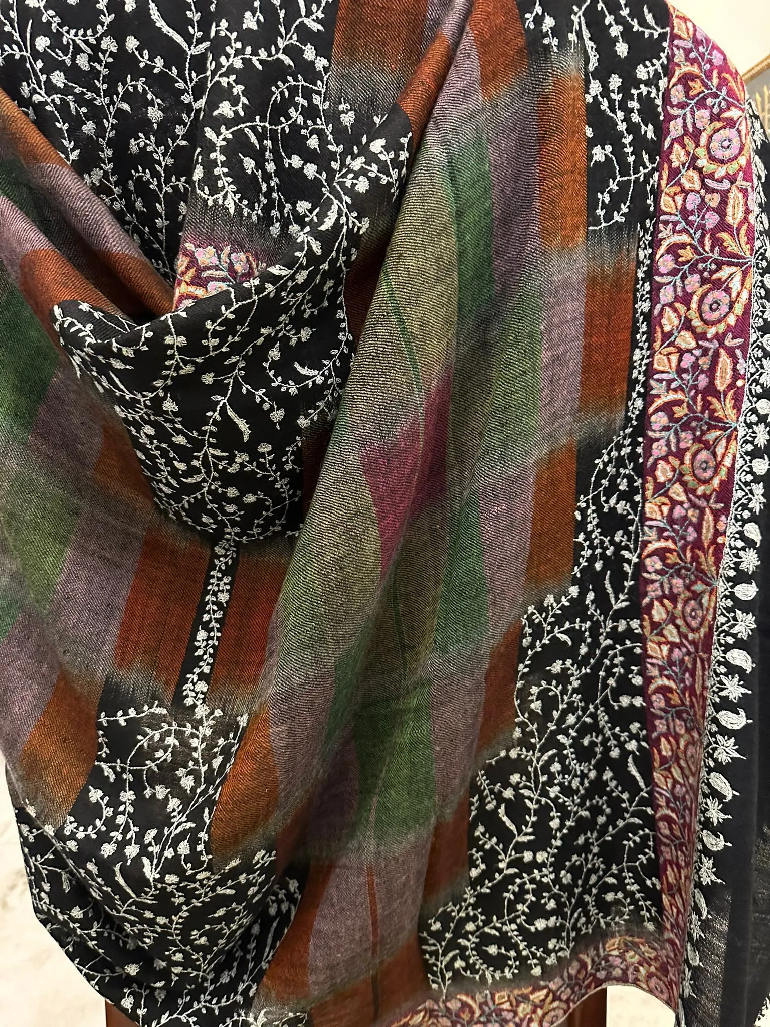 Shawl with a black and ivory needlework jaal beside multicoloured check panels.