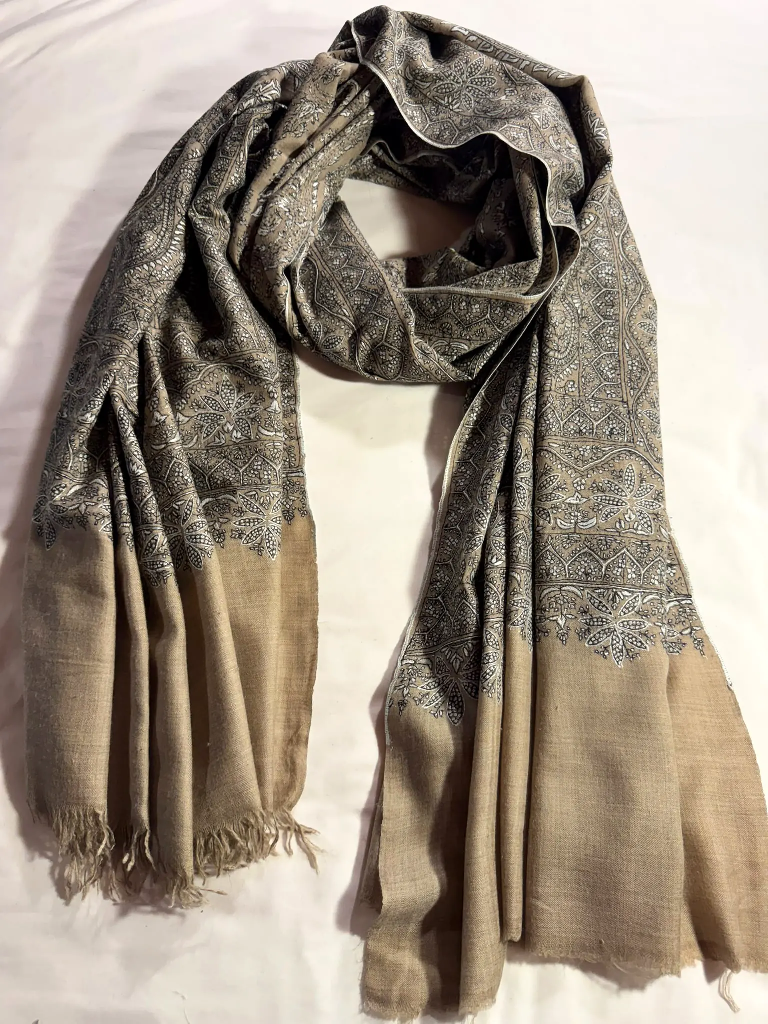 Shawl covered in dense charcoal needlework with plain beige ends.