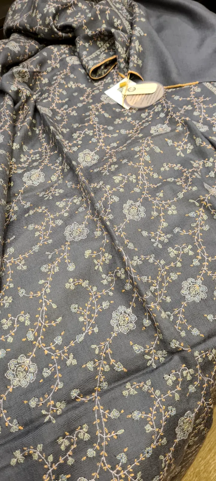 Grey shawl covered edge to edge in a fine ivory vine pattern of needlework.