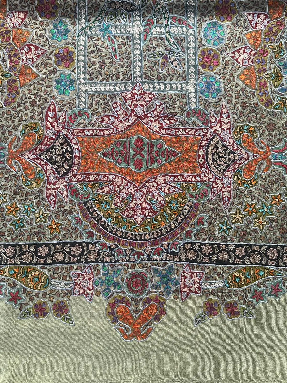 Sage green kalamkari shawl with a central medallion in orange, rose and teal, framed by scattered flowers and a black border.