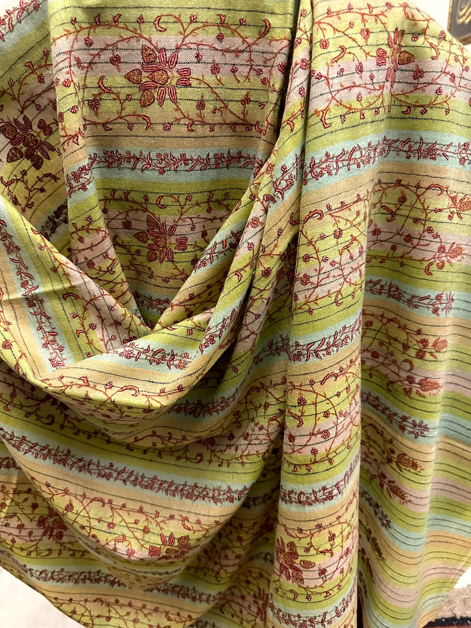 Pale lime striped shawl with red floral vine needlework, draped.