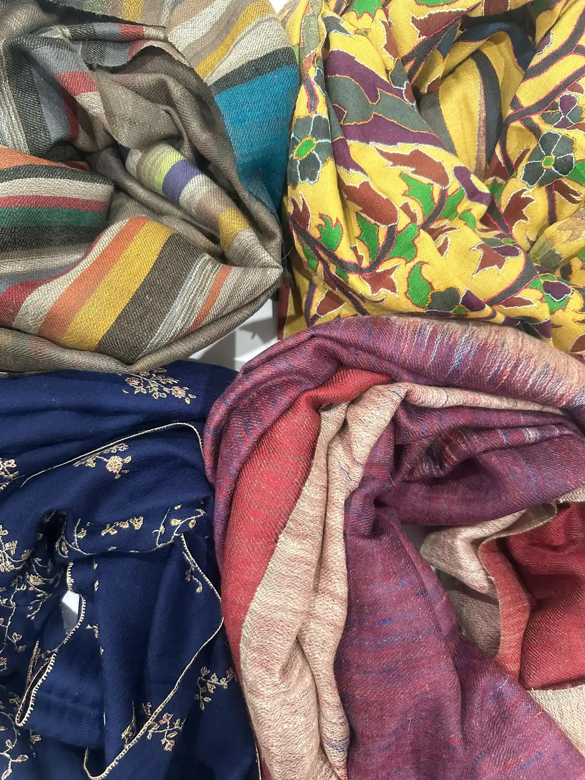 Folded stoles: yellow paisley, embroidered navy, stripes and ikat.