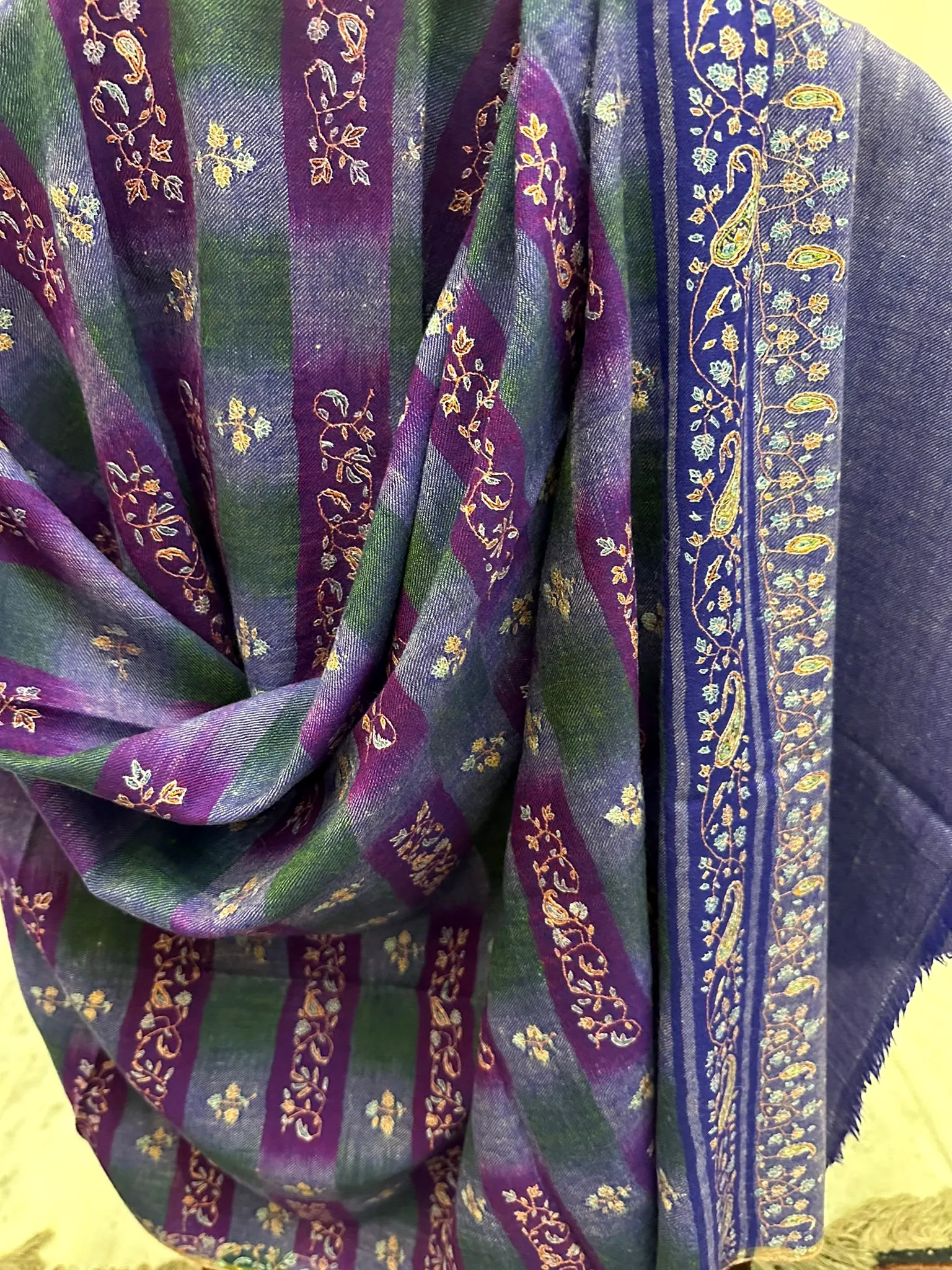 Purple and green ikat shawl with gold needlework stripes, draped.