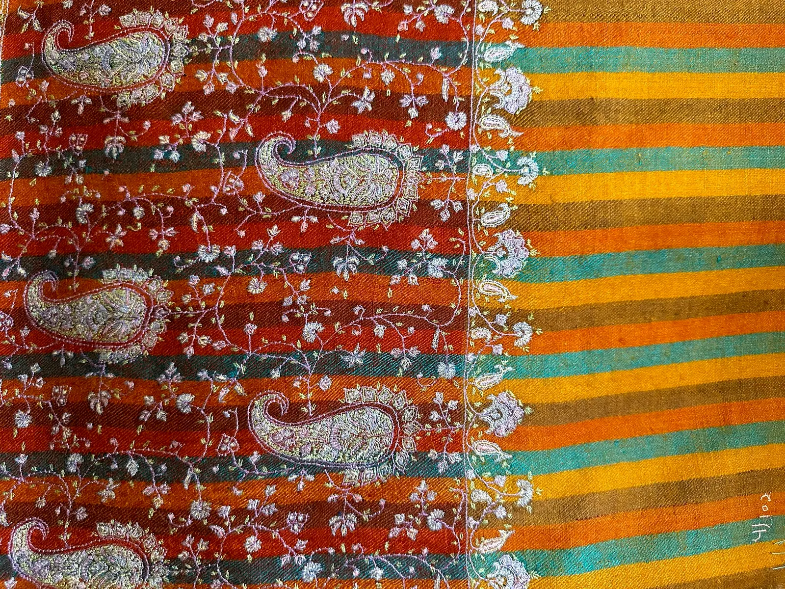 Flat view of the same shawl, showing ivory paisleys on the orange band beside the saffron and teal stripes.