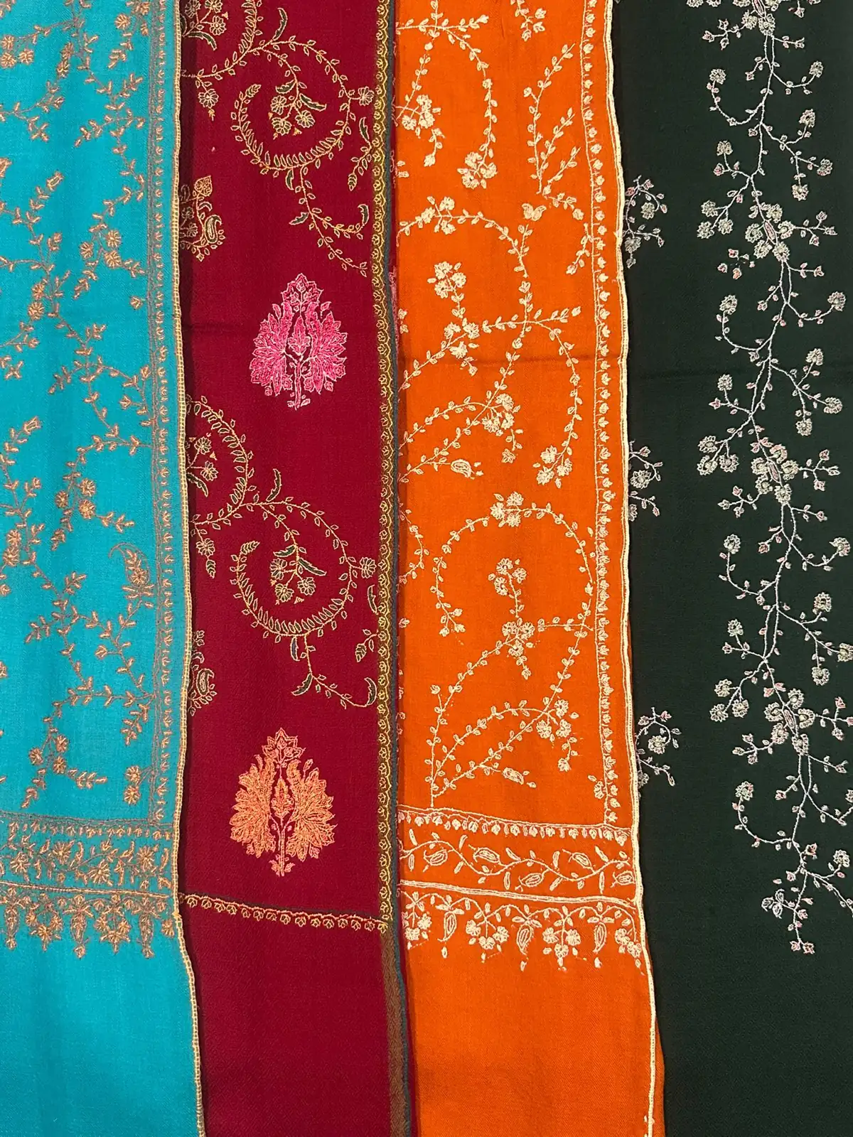 Four sozni stoles side by side in turquoise, crimson, orange and green.