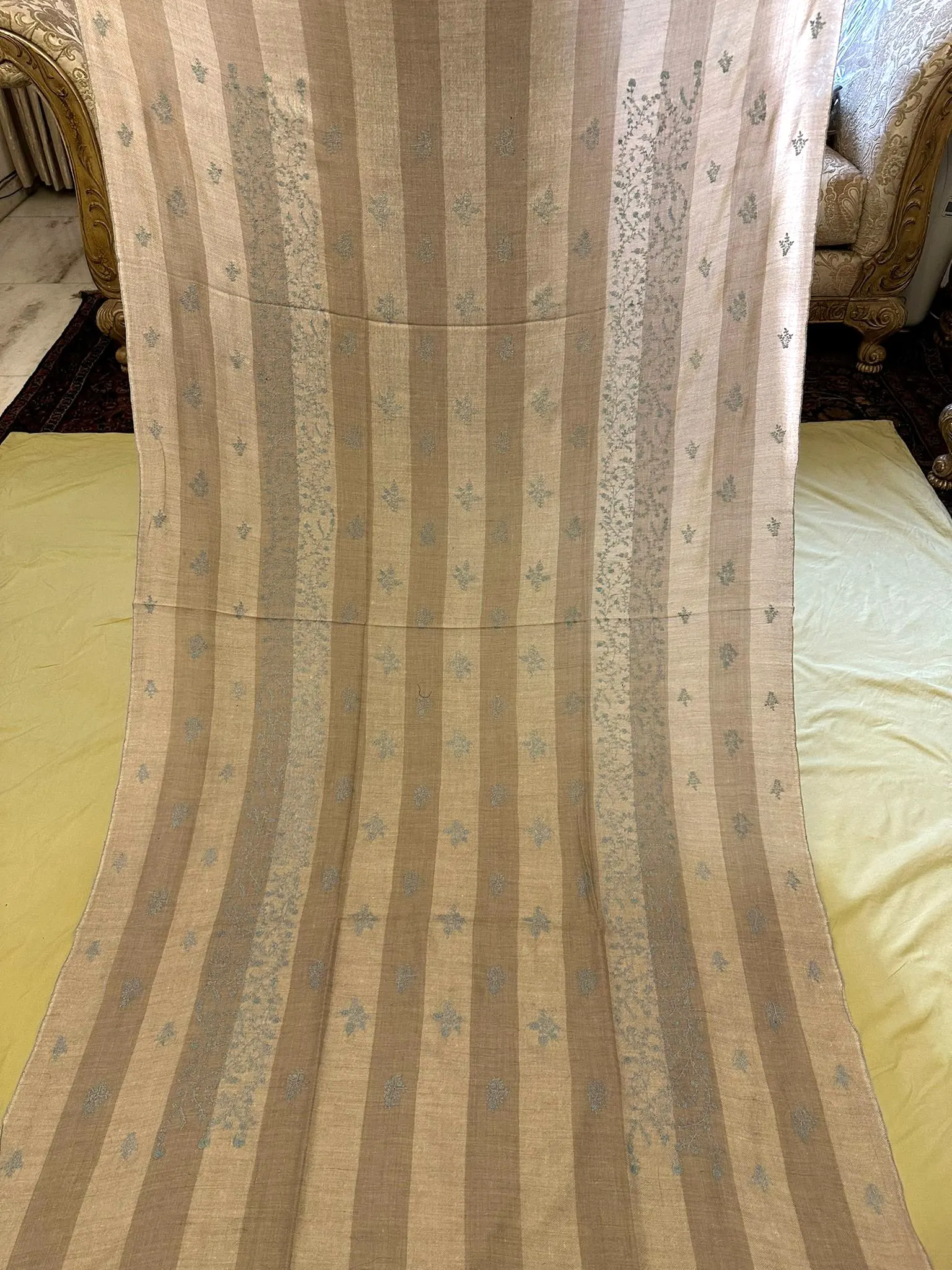 Stone striped shawl with pale blue needlework lines, laid out full length.